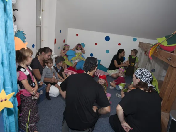 Děti a učitelé sedí spolu v kruhu na zemi